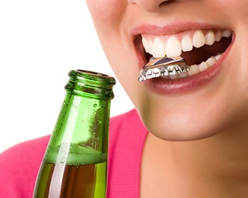 Woman with bottle cap between teeth at risk of toothache in Lincoln