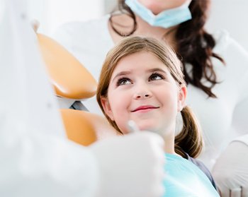 young girl smiling up at dentist