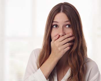 young woman covering her mouth and wondering why implants fail