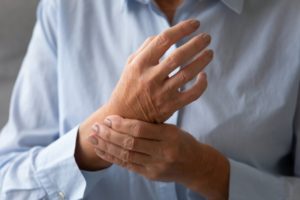 person holding their hand with rheumatoid arthritis and wondering if they can get dental implants